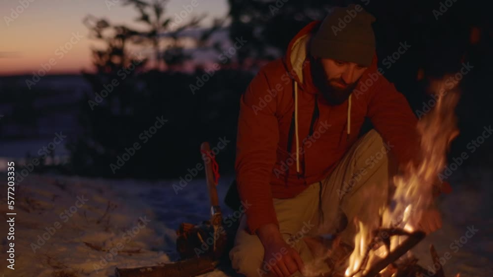 A tourist makes a fire in a winter forest. The concept of hiking and active recreation. A tourist makes a fire in a winter forest. The concept of hiking and active recreation.