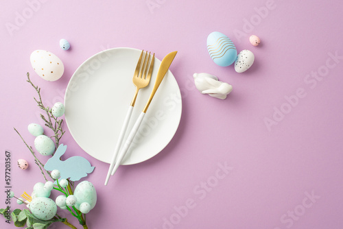 Easter decorations concept. Top view photo of plate cutlery fork knife bouquet with easter eggs and ceramic bunny on isolated lilac background with empty space