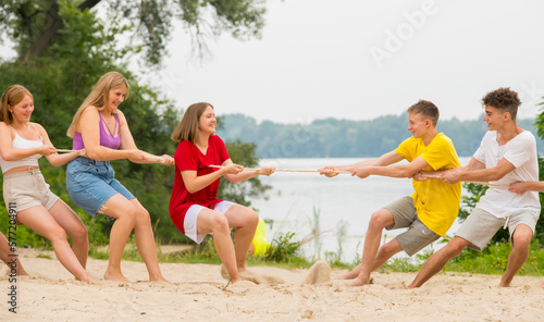 a group of teenagers playing tug of war on the beach