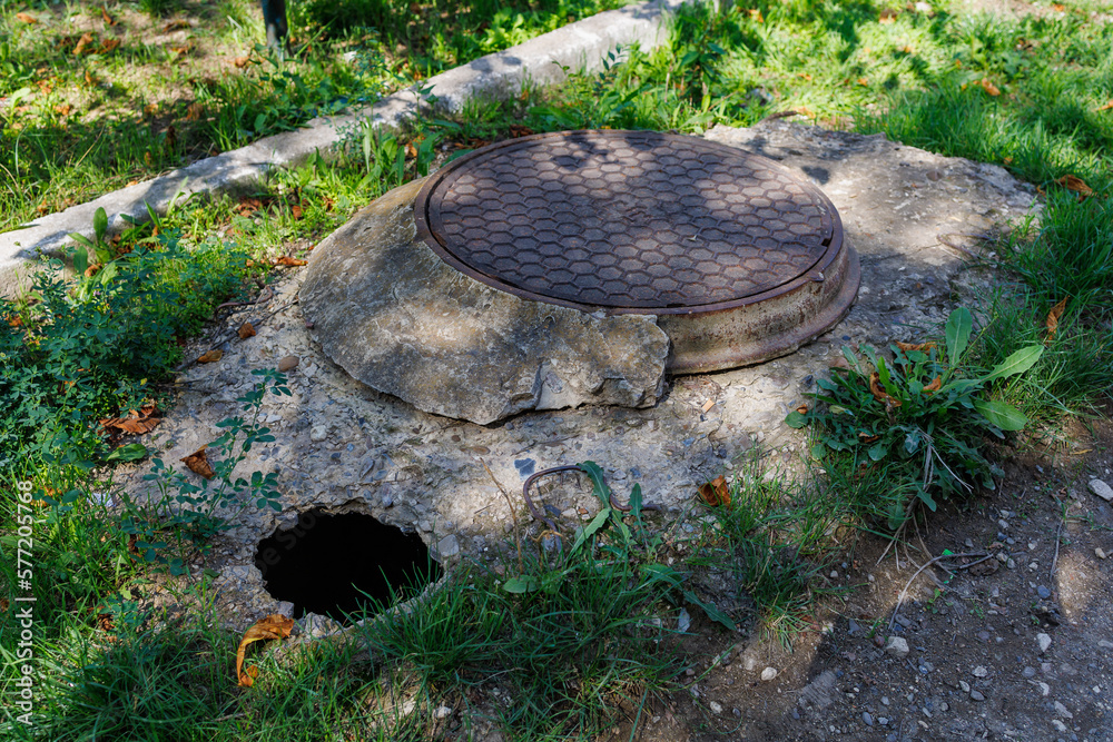 Naklejka premium Dangerous pit of failed asphalt near the sewer manhole. Background with selective focus and copy space