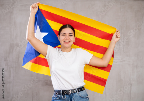 Young positive woman holding national flag of Catalonia in her hands
