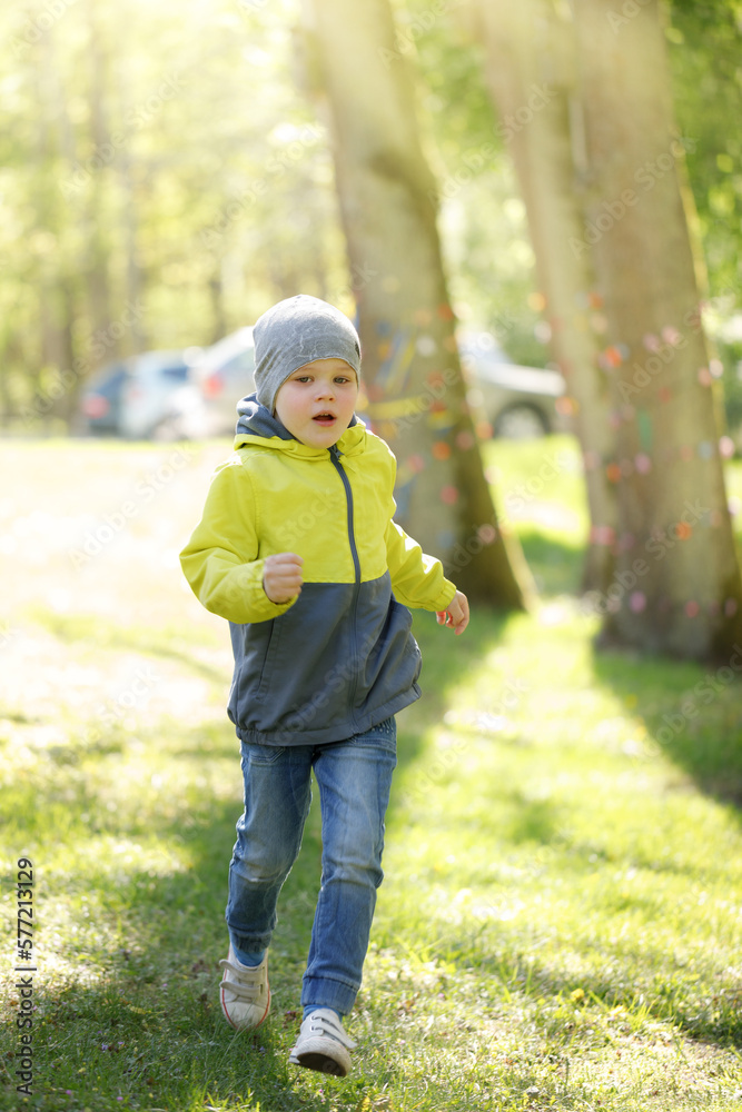 Little cute boy running in the spring park on the background of sunlight. Concept - spending time in nature, movement, child's joy in warm spring weather Little cute boy running in the spring park on the background of sunlight. Concept - spending time in nature, movement, child's joy in warm spring weather