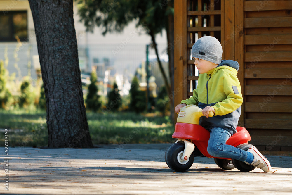 Active little boy having fun and driving red little toy bike. Active little boy having fun and driving red little toy bike.