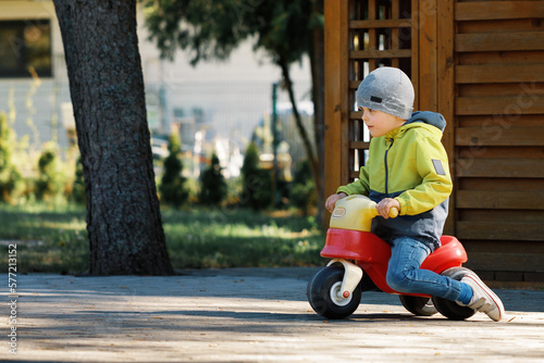 Active little boy having fun and driving red little toy bike.