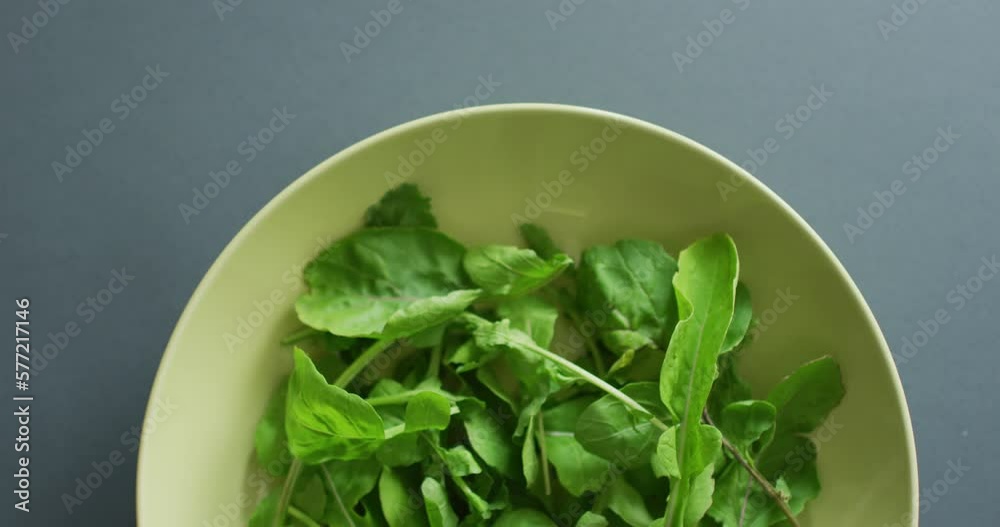 Video of close up of bowl of fresh salad leaves on grey background Video of close up of bowl of fresh salad leaves on grey background