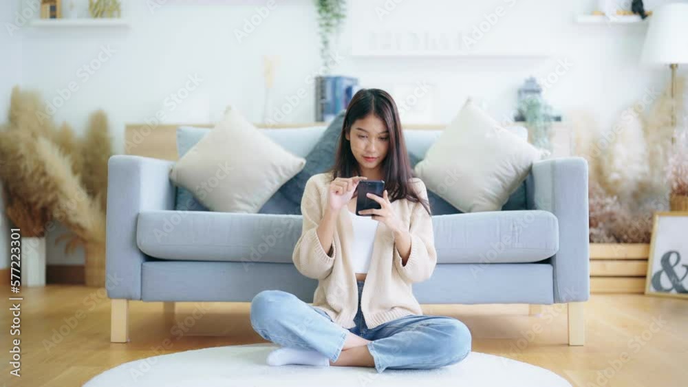 Happy young asian woman relax on comfortable couch at home texting messaging on smartphone, smiling girl use cellphone, chatting online message, shopping online from home Happy young asian woman relax on comfortable couch at home texting messaging on smartphone, smiling girl use cellphone, chatting online message, shopping online from home