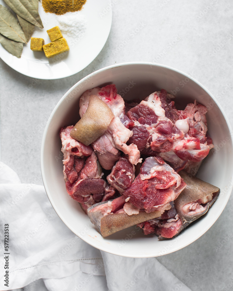 Fresh raw goat meat in a white bowl, chopped goat meat being prepared for cooking Fresh raw goat meat in a white bowl, chopped goat meat being prepared for cooking