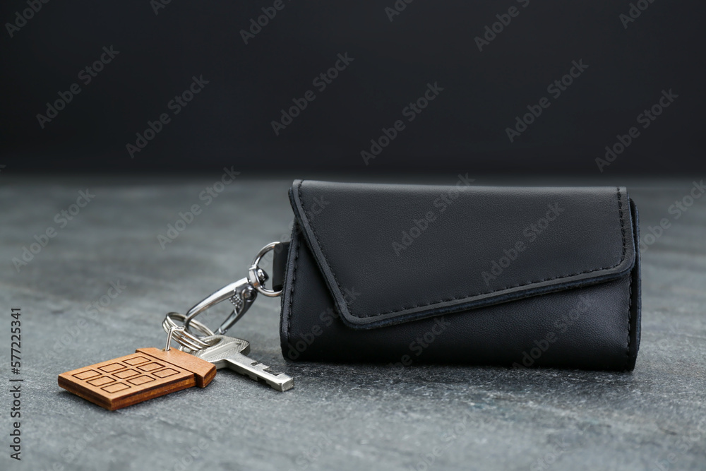 Leather case with key on grey table, closeup Leather case with key on grey table, closeup