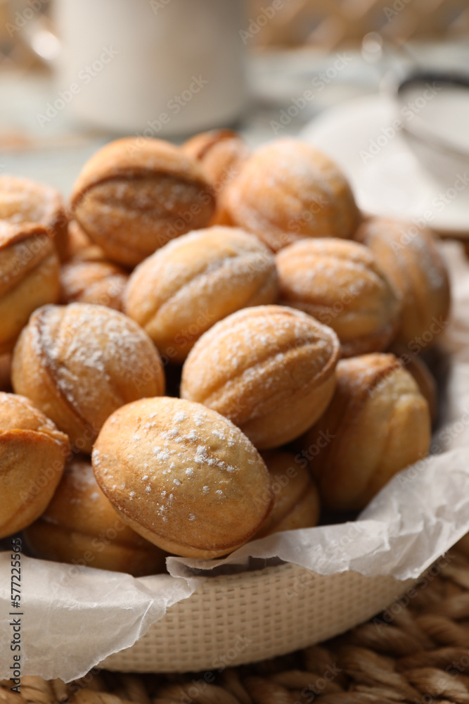 Bowl of delicious nut shaped cookies on wicker mat, closeup