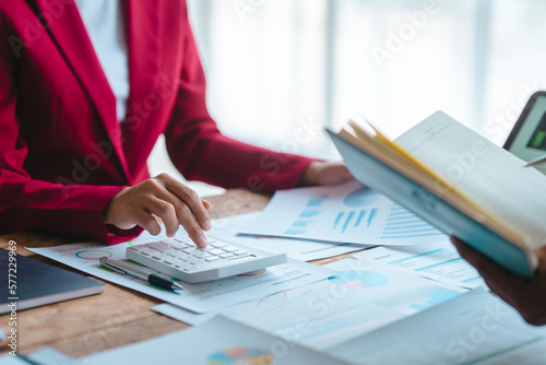Close up bookkeepers working with balance sheet to analyze problems and find solutions to bringing develop business organization and company's stock market system. Using calculator
