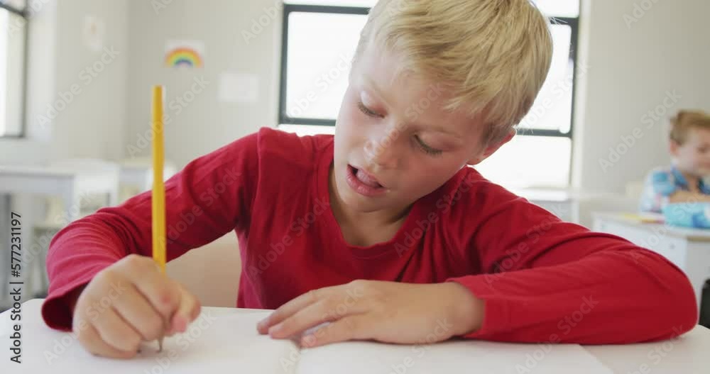 Video of happy caucasian boy sitting at school desk and writing Video of happy caucasian boy sitting at school desk and writing