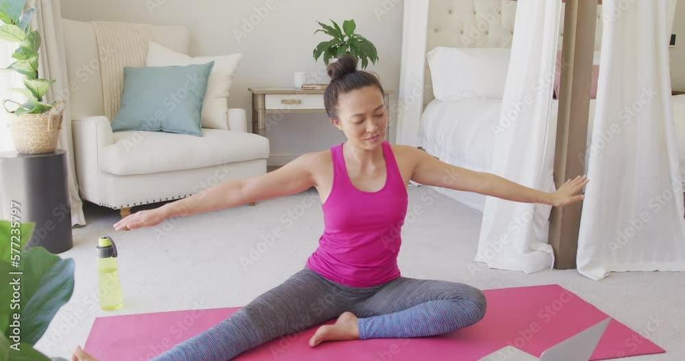 Happy asian woman doing yoga and stretching in bedroom, in slow motion