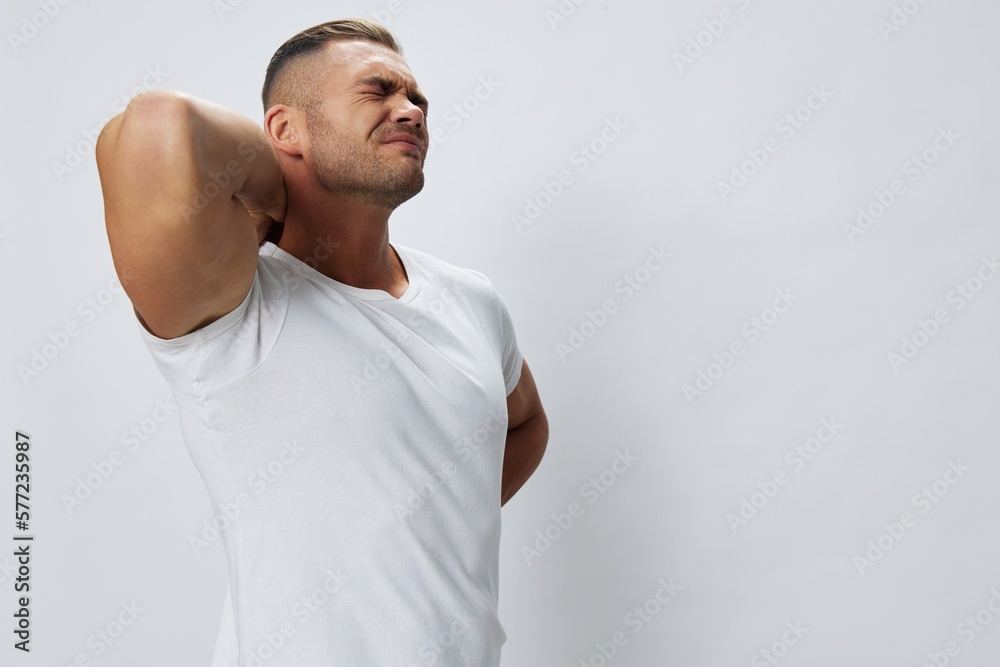 Man back pain neck and joints, bone and spine problems, inflammation and trauma, in white T-shirt on white isolated background, copy space Man back pain neck and joints, bone and spine problems, inflammation and trauma, in white T-shirt on white isolated background, copy space