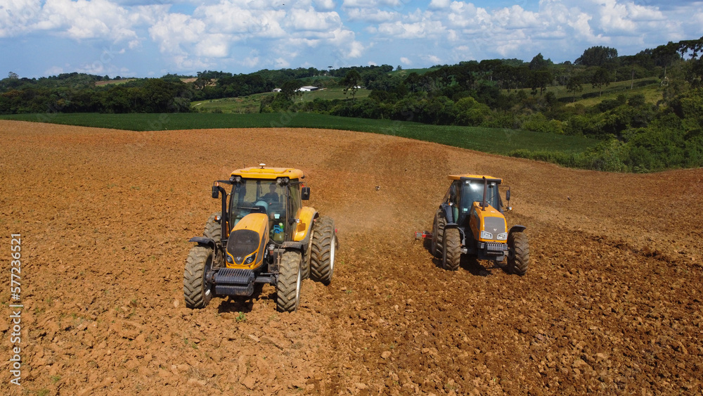 Obraz premium Aerial view of two tractors working in the field