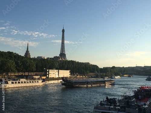Photo of the Eiffel Tower in Paris, France overlooking La Seine River and a boat cruise. 