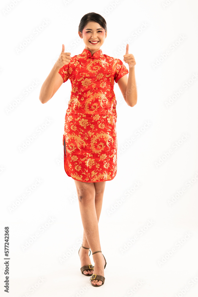 beautiful asian woman in cheongsam standing cross legged with thumbs up and smiling beautiful asian woman in cheongsam standing cross legged with thumbs up and smiling