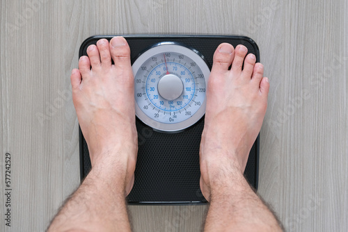 Legs of men standing on scales weight. Concept of health and weight loss.