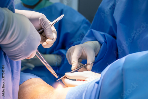 Doctor in blue uniform do surgery inside operating room in orthopedic hospital.Surgeon made suture on skin.Surgeon hold medical equipment to do surgery in operating theatre with space.Medical concept.