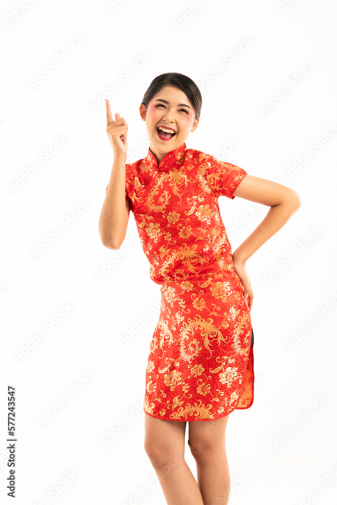 young asian woman in red cheongsam standing cross legged put her left hand on her hips and the another one pointing her forefinger young asian woman in red cheongsam standing cross legged put her left hand on her hips and the another one pointing her forefinger