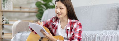 Fényképezés Asian woman specializes in music is composing the lyrics and melody for the opening of a new single, Using imagination and concentration in creating music, acoustic guitar, Creation of music notes