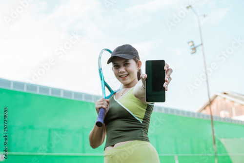 bottom view of female tennis player holding racket showing mobile phone screen on tennis court © Odua Images