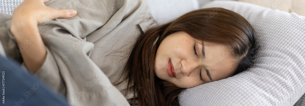 Woman lying chills with high fever on sofa, Severe illness, Headache, Sore throat, High fever, Not taking care of your physical health and not exercising causes your immune system to be low.. Woman lying chills with high fever on sofa, Severe illness, Headache, Sore throat, High fever, Not taking care of your physical health and not exercising causes your immune system to be low..
