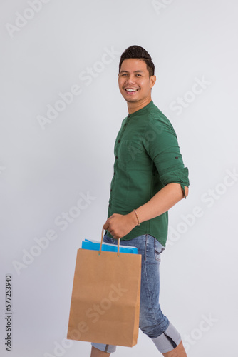 asian man smiling while walking and bring the shopping bags on isolated background