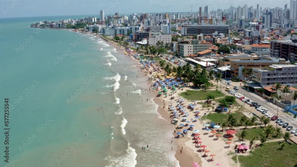 Rising aerial shot of intermares beach in Cabedelo, Brazil with Brazilians and tourists enjoying the ocean near the costal capital of Joao Pessoa in the state of Paraiba on a warm sunny summer day.