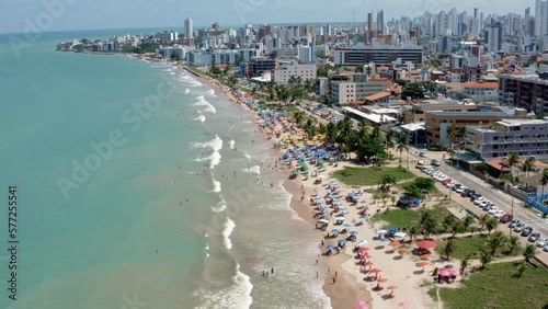 Rising aerial shot of intermares beach in Cabedelo, Brazil with Brazilians and tourists enjoying the ocean near the costal capital of Joao Pessoa in the state of Paraiba on a warm sunny summer day. photo