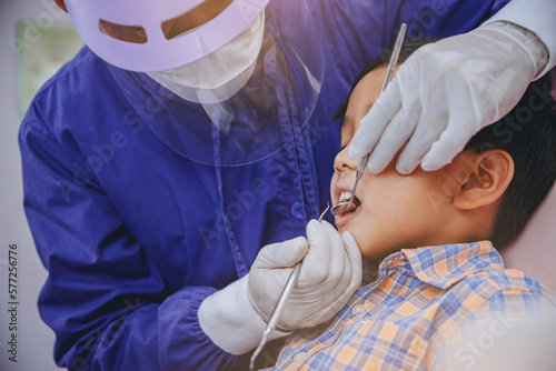 Dentist examines child's teeth using metal instruments at dental clinic. Dentistry and healthcare concept