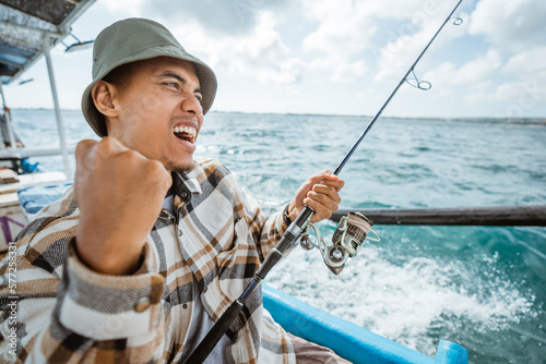 excited Asian fisherman on Strike when fishing with a small fishing boat at sea