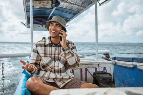 anglers chat on cell phones during a break sitting on a fishing boat at sea