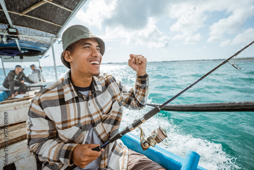 excited fisherman with his hands clenched while fishing in a small fishing boat at sea