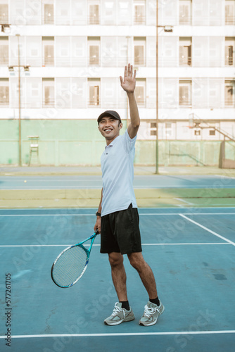 male tennis player smiling and waving after the match on the tennis court © Odua Images