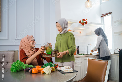 muslim woman serving drink for her friend and family at home having dinner together photo