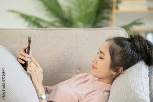 Asian woman Lie down at the sofa to relax on the holidays.