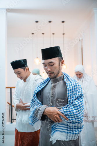 Asian men in caps perform iftitah prayer movements during congregational prayers photo