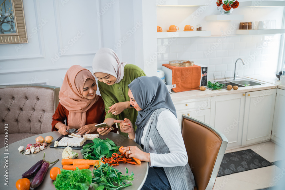 three friend with hijab looking at the phone searching for new recipe for dinner three friend with hijab looking at the phone searching for new recipe for dinner