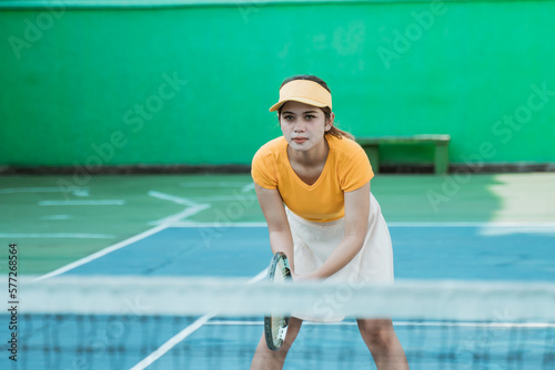 female tennis player concentrating in a position ready to receive the opponent's ball while holding a racket on the tennis court © Odua Images