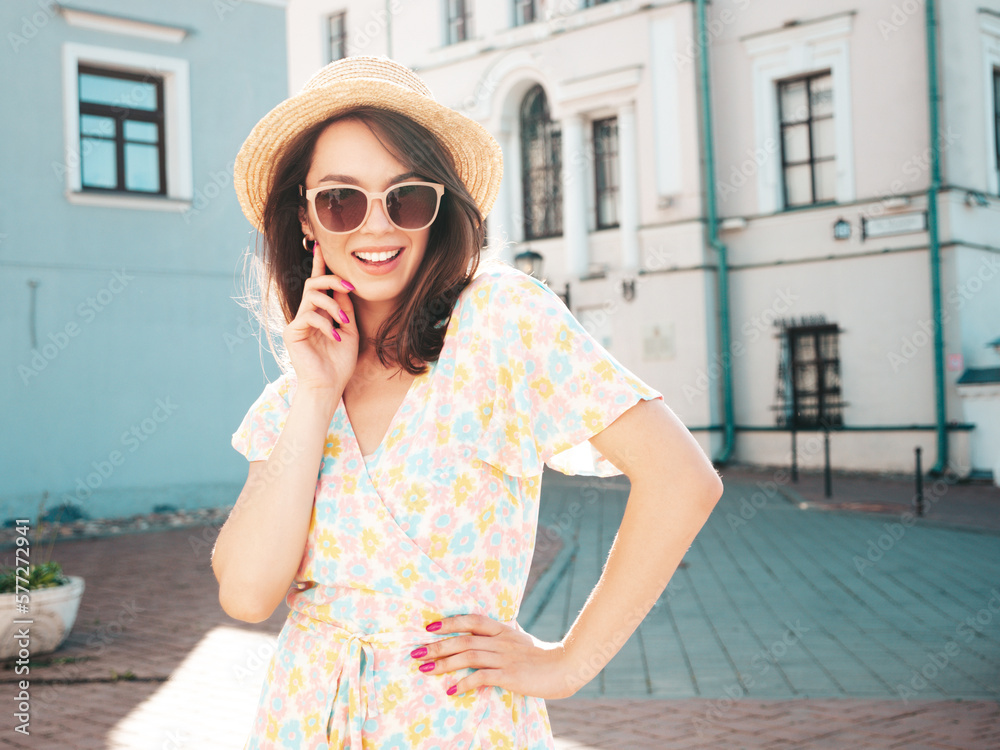 Beautiful smiling brunette model. Trendy female posing in the street background. Funny and positive woman having fun outdoors at sunset. In hat at sunny day. In dress, sunglasses