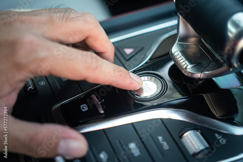 Action of a driver is pressing on the engine start button to starting the car. Close-up and selective focus.