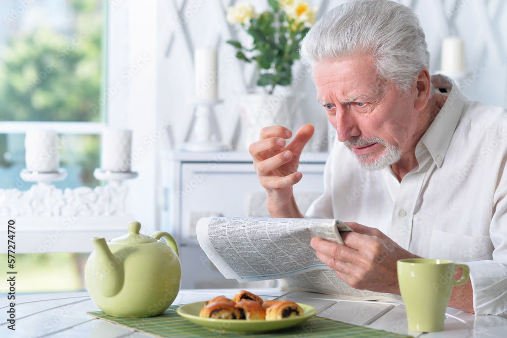 Emotional senior man reading newspaper Emotional senior man reading newspaper