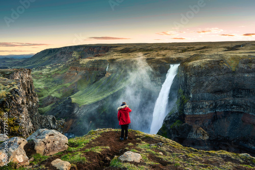 Haifoss waterfall flowing in volcanic canyon and traveler taking a picture among the Icelandic Highlands in summer © Mumemories