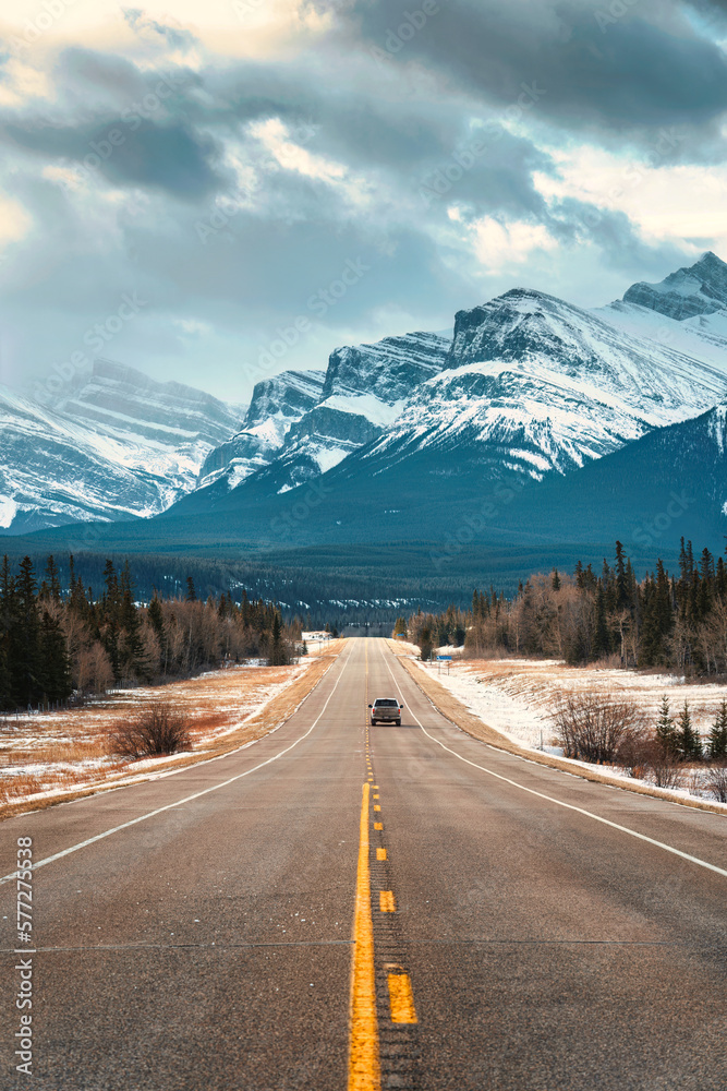 Naklejka premium Road trip on highway between pine forest driving straight to rocky mountains in Icefields Parkway
