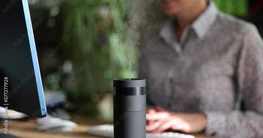 Working on computer next to aroma oil diffuser on table