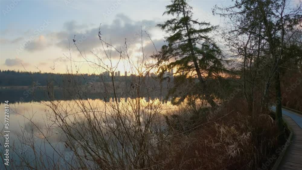 Trail by Peaceful Lake in the modern city, Deer Lake Park. Burnaby, Vancouver, BC, Canada. Colorful Winter Sunset Sky. Slow Motion Cinematic Pan. Trail by Peaceful Lake in the modern city, Deer Lake Park. Burnaby, Vancouver, BC, Canada. Colorful Winter Sunset Sky. Slow Motion Cinematic Pan.