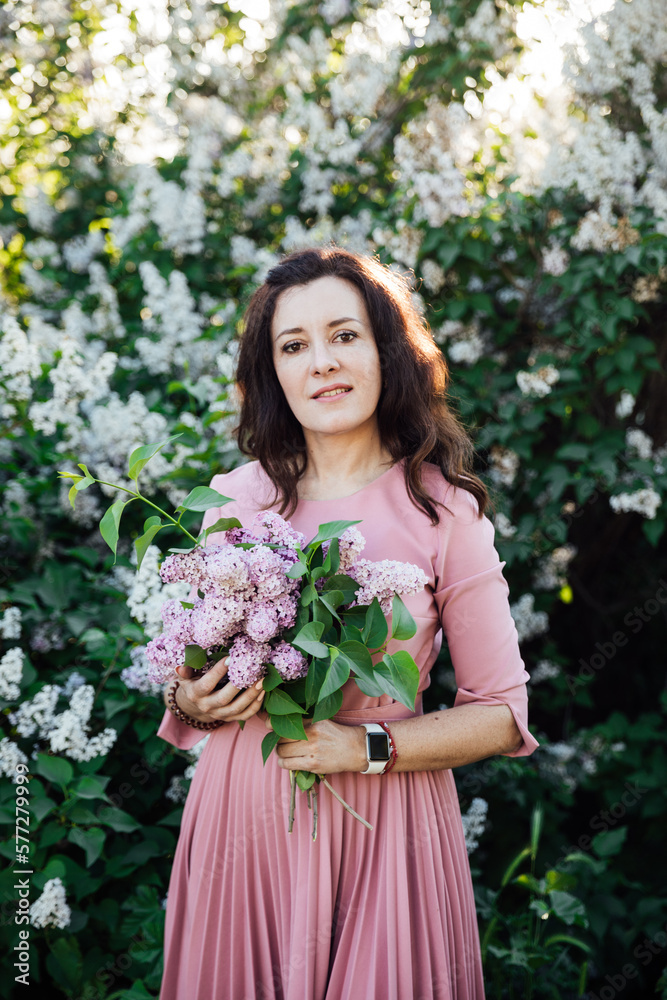 beautiful woman with a bouquet of lilacs on a background of flowers