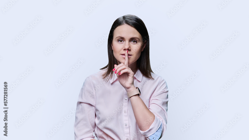 Young woman showing finger on lips gesture on white background Young woman showing finger on lips gesture on white background