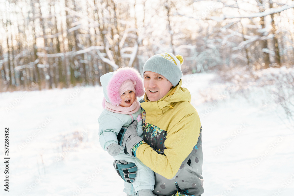 A man of 35-40 years old holds a one year old daughter in winter