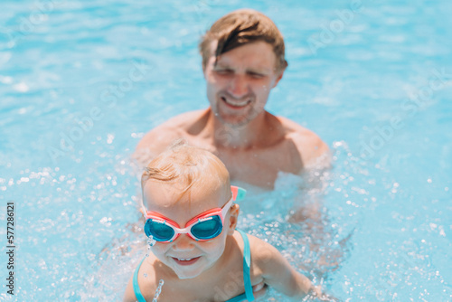 Dad teaches two-year-old daughter to swim in the outdoor pool © Cavan